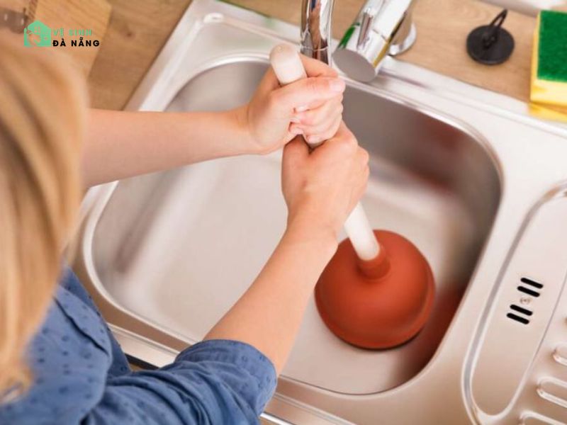 Dùng móc sắt hoặc dụng cụ thông bồn cầu